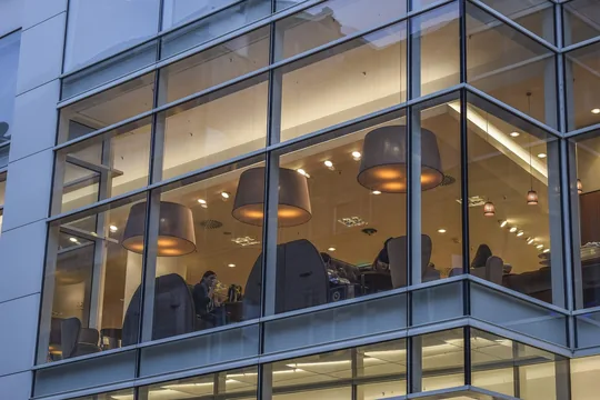 A modern glass office building with lit interiors